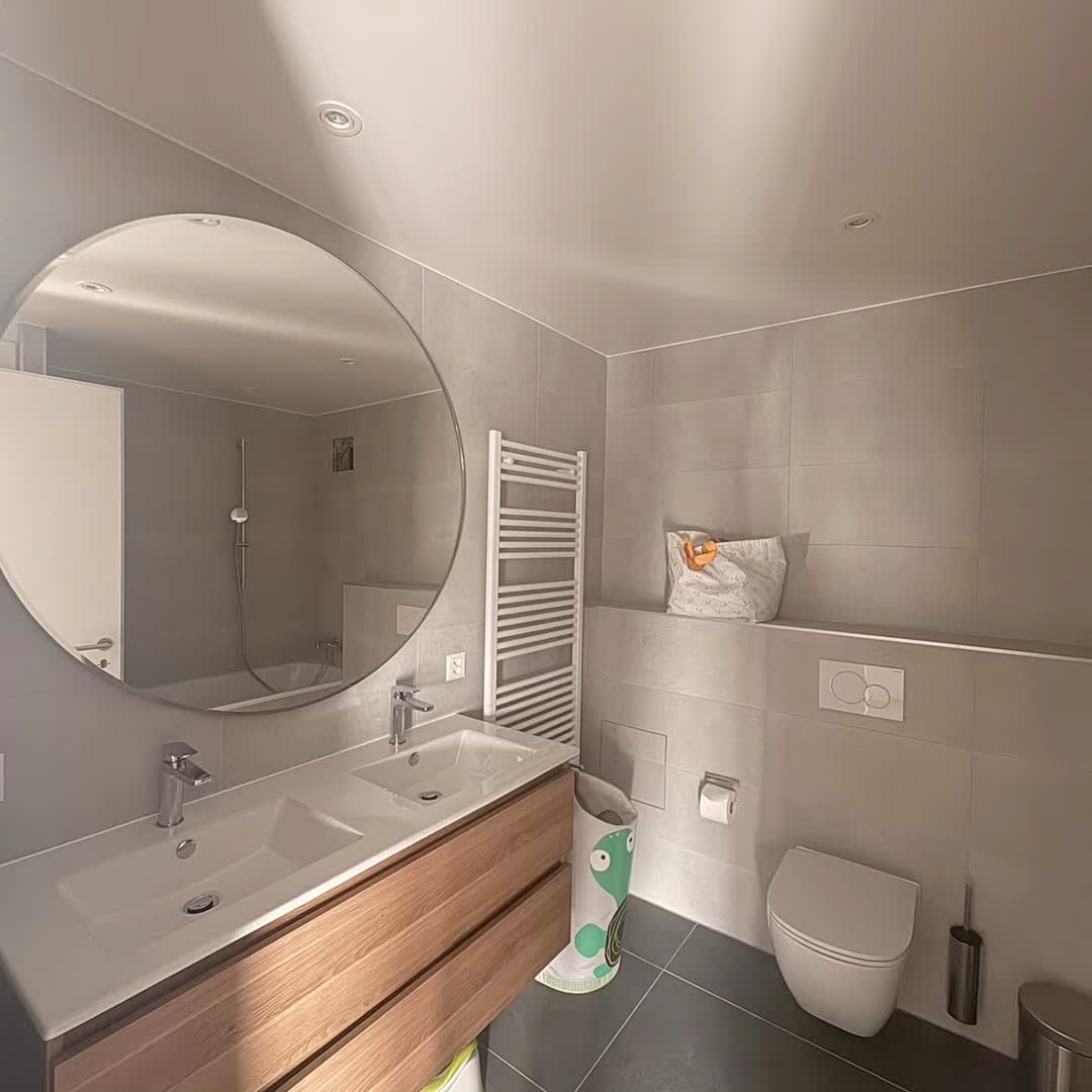 Double vasque, miroir rond et carrelage clair